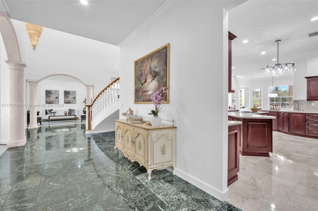 hallway with sink, ornamental molding, and decorative columns