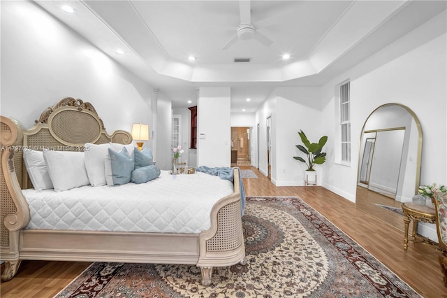 bedroom featuring ceiling fan, hardwood / wood-style flooring, and a raised ceiling