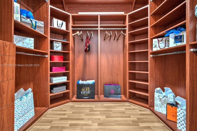 walk in closet with light hardwood / wood-style flooring