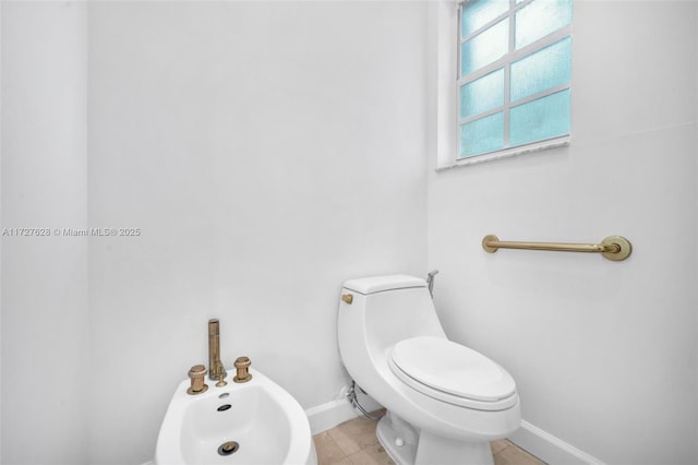 bathroom with a bidet, toilet, and tile patterned flooring