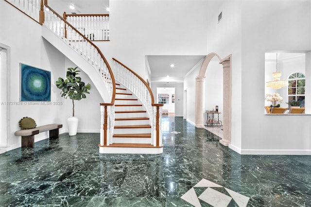 entryway with a notable chandelier, a high ceiling, and ornate columns