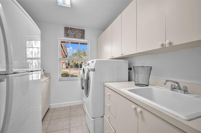 washroom with washing machine and dryer, light tile patterned flooring, sink, and cabinets