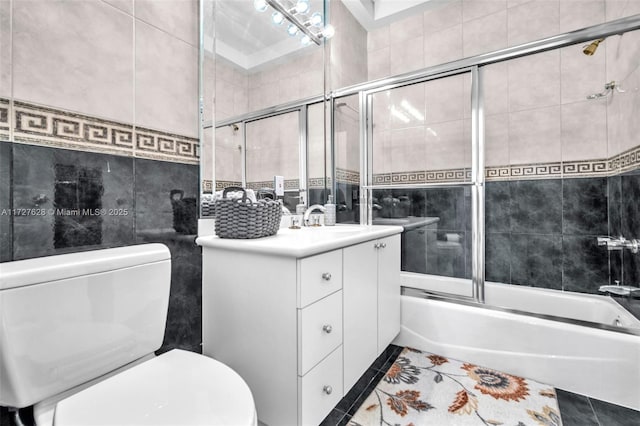 full bathroom featuring bath / shower combo with glass door, tile walls, tile patterned floors, and vanity