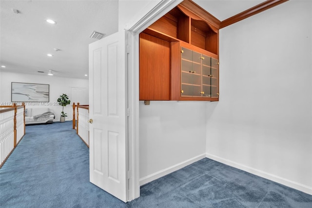 hallway with ornamental molding and carpet floors