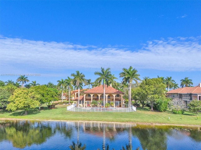 back of house featuring a water view and a lawn