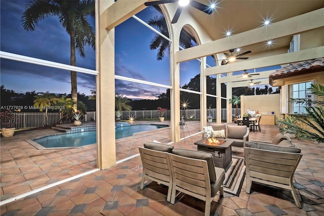 patio terrace at dusk with ceiling fan, a fenced in pool, and a fire pit