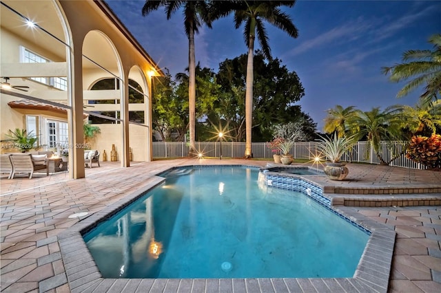 pool at dusk with french doors, a patio, and an in ground hot tub