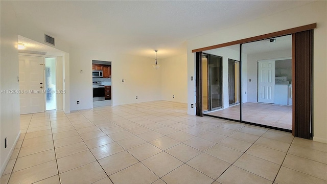 empty room featuring washer / clothes dryer and light tile patterned flooring