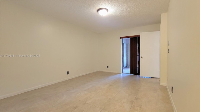 tiled empty room featuring a textured ceiling