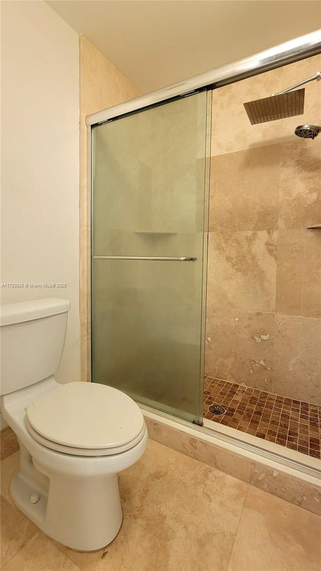 bathroom featuring toilet and a shower with shower door