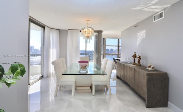 dining area with a textured ceiling, floor to ceiling windows, a chandelier, and a water view