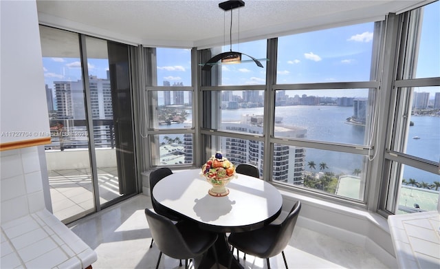 dining area featuring a textured ceiling and a water view