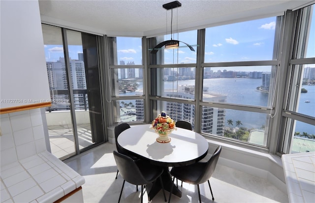 dining area with a water view and a textured ceiling