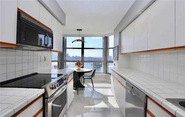 kitchen with a water view, white cabinets, decorative backsplash, and appliances with stainless steel finishes