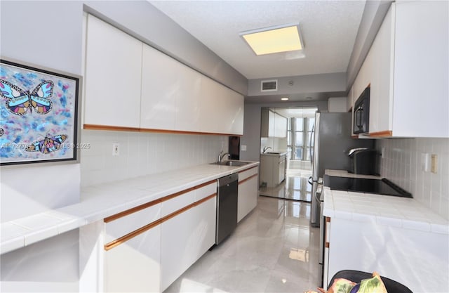 kitchen featuring appliances with stainless steel finishes, white cabinetry, tasteful backsplash, and sink