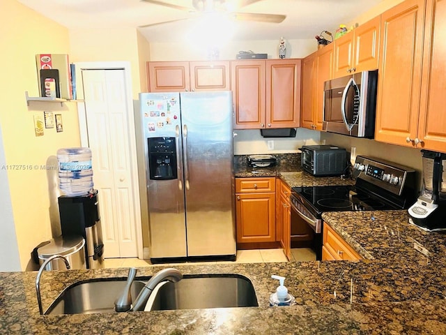 kitchen featuring ceiling fan, sink, appliances with stainless steel finishes, and dark stone counters