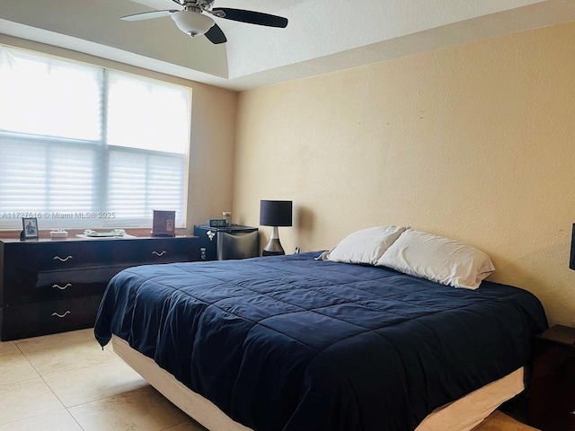 tiled bedroom featuring ceiling fan and a raised ceiling