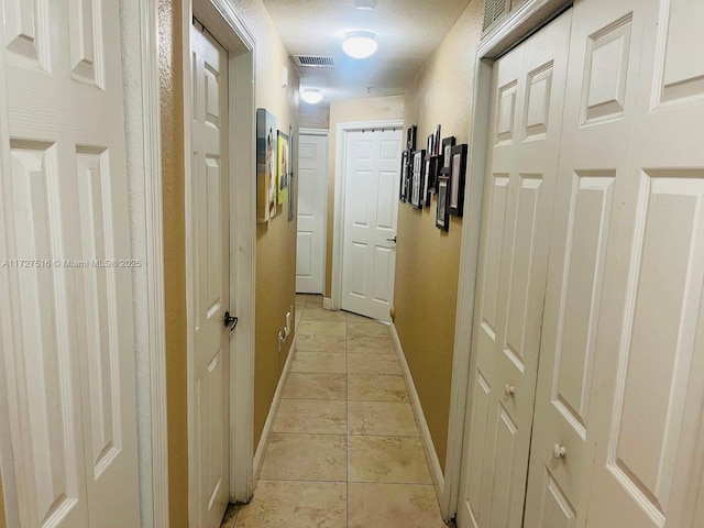 corridor with a textured ceiling and light tile patterned floors