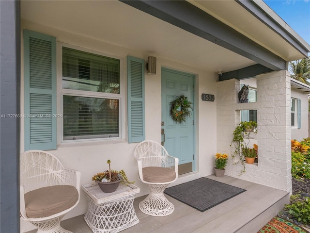 doorway to property featuring stucco siding and a porch