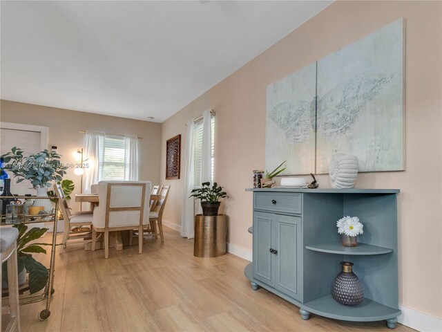 kitchen with a kitchen bar, light wood-type flooring, appliances with stainless steel finishes, kitchen peninsula, and white cabinets