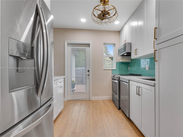 kitchen featuring light hardwood / wood-style flooring, stainless steel appliances, decorative backsplash, white cabinets, and decorative light fixtures