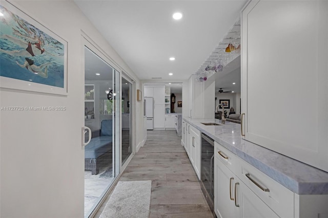 kitchen with sink, white cabinetry, light hardwood / wood-style flooring, white fridge, and beverage cooler