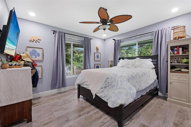 bedroom with multiple windows, light hardwood / wood-style floors, and ceiling fan