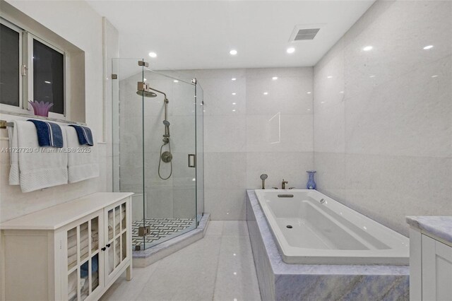 bathroom featuring tile patterned flooring, plus walk in shower, tile walls, and vanity