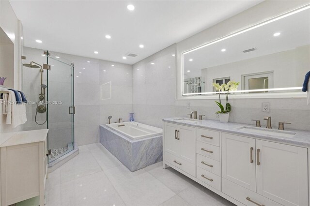 bathroom with tile patterned floors, plus walk in shower, vanity, and tile walls