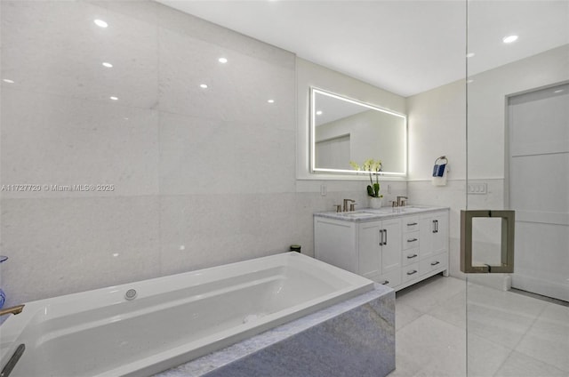 bathroom with vanity, tile walls, tile patterned floors, and a relaxing tiled tub