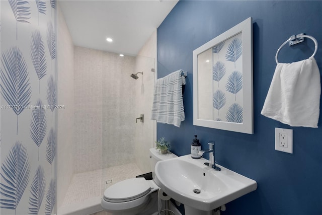 bathroom featuring sink, toilet, and tiled shower