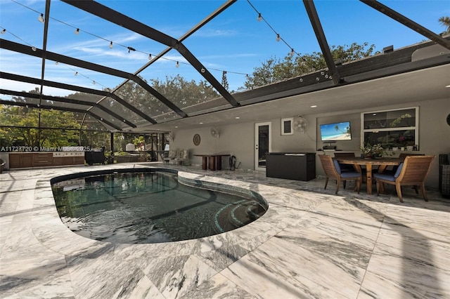 view of pool featuring a patio, glass enclosure, and exterior kitchen