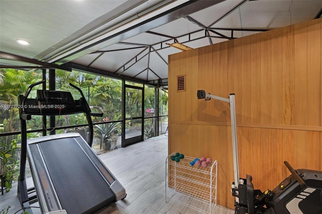 exercise area with expansive windows, wood-type flooring, and wooden walls