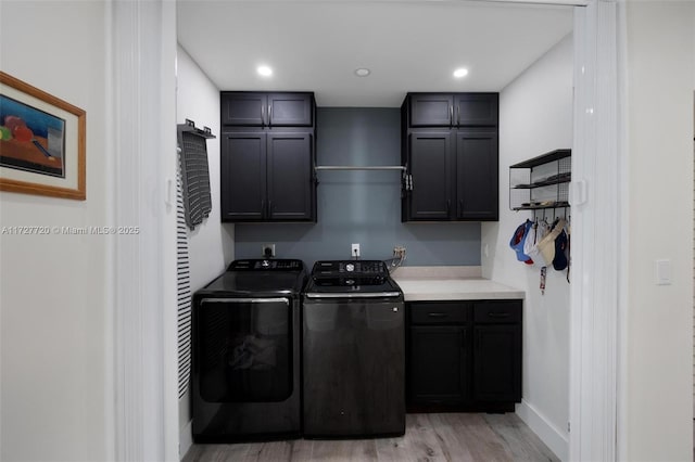 clothes washing area with cabinets, washer and clothes dryer, and light hardwood / wood-style flooring