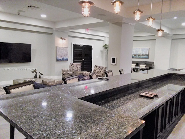 kitchen with hanging light fixtures, a breakfast bar, and dark stone counters