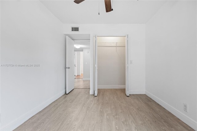 unfurnished bedroom featuring ceiling fan, light hardwood / wood-style flooring, and a closet