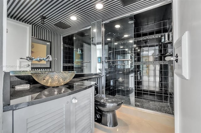 bathroom featuring vanity, a shower with door, tile patterned floors, and toilet