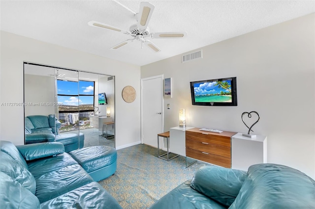 living room featuring ceiling fan and a textured ceiling