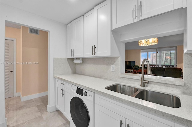 kitchen featuring light stone countertops, white cabinets, washer / dryer, sink, and backsplash