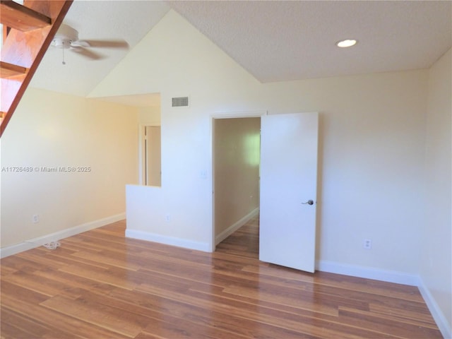 empty room with ceiling fan, a textured ceiling, dark hardwood / wood-style flooring, and vaulted ceiling