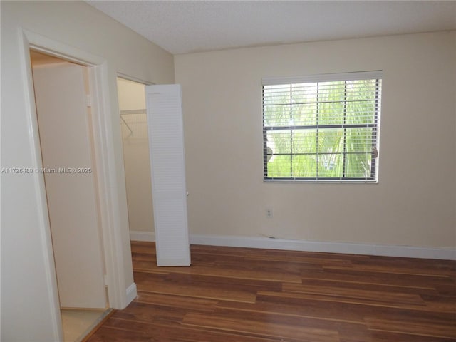 unfurnished bedroom with dark hardwood / wood-style floors, a closet, and a walk in closet