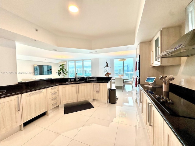 kitchen featuring wall chimney range hood, a wealth of natural light, kitchen peninsula, and light tile patterned floors