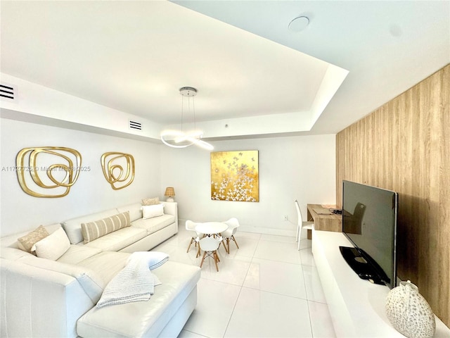 tiled living room featuring a raised ceiling and wood walls