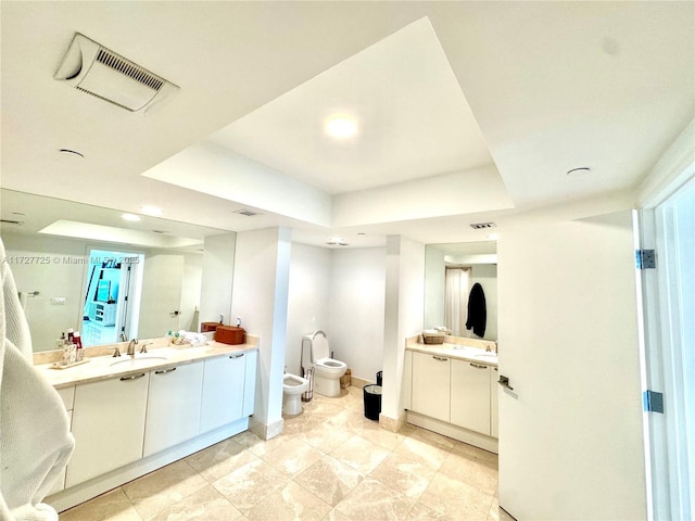 bathroom with a bidet, a tray ceiling, vanity, and toilet