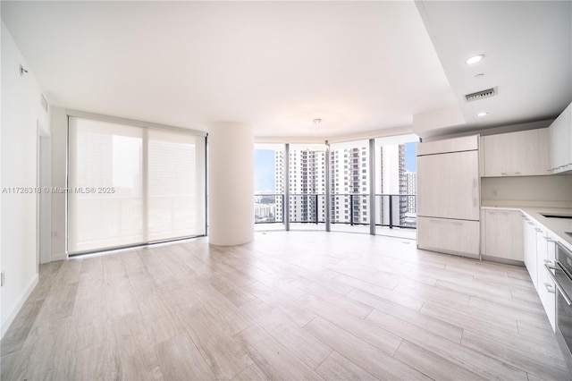 kitchen featuring decorative light fixtures, light hardwood / wood-style flooring, expansive windows, and paneled fridge