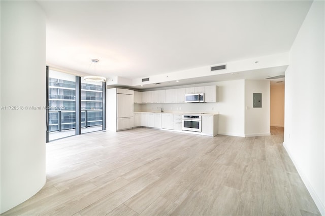 unfurnished living room with sink, electric panel, floor to ceiling windows, and light hardwood / wood-style flooring