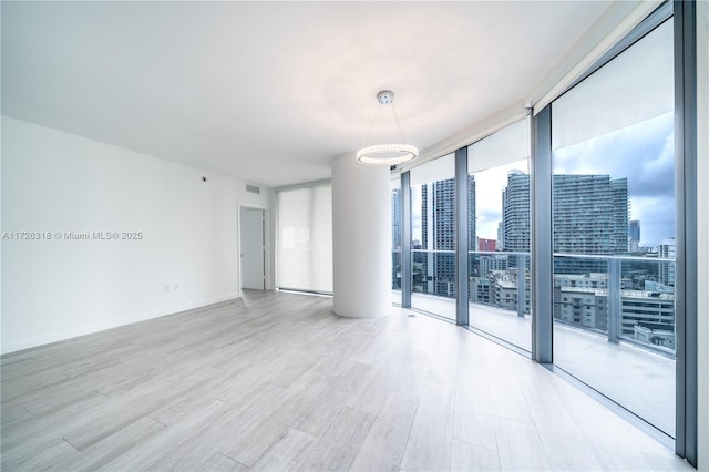 unfurnished room featuring floor to ceiling windows and light hardwood / wood-style flooring