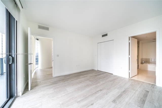 unfurnished bedroom with light hardwood / wood-style floors and ensuite bath