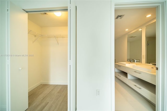 walk in closet with sink and light wood-type flooring