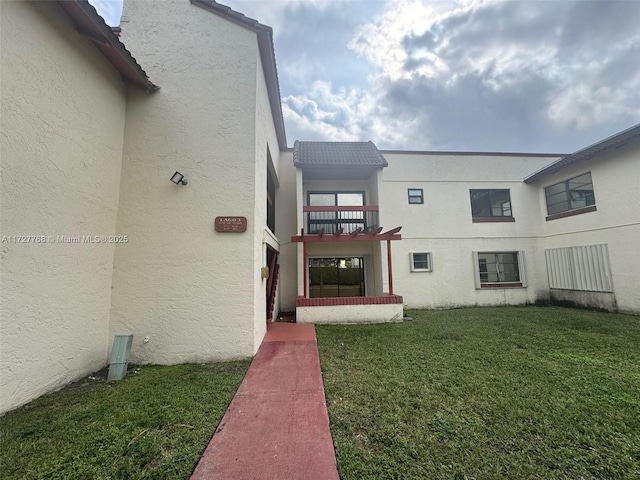 property entrance with a balcony and a yard